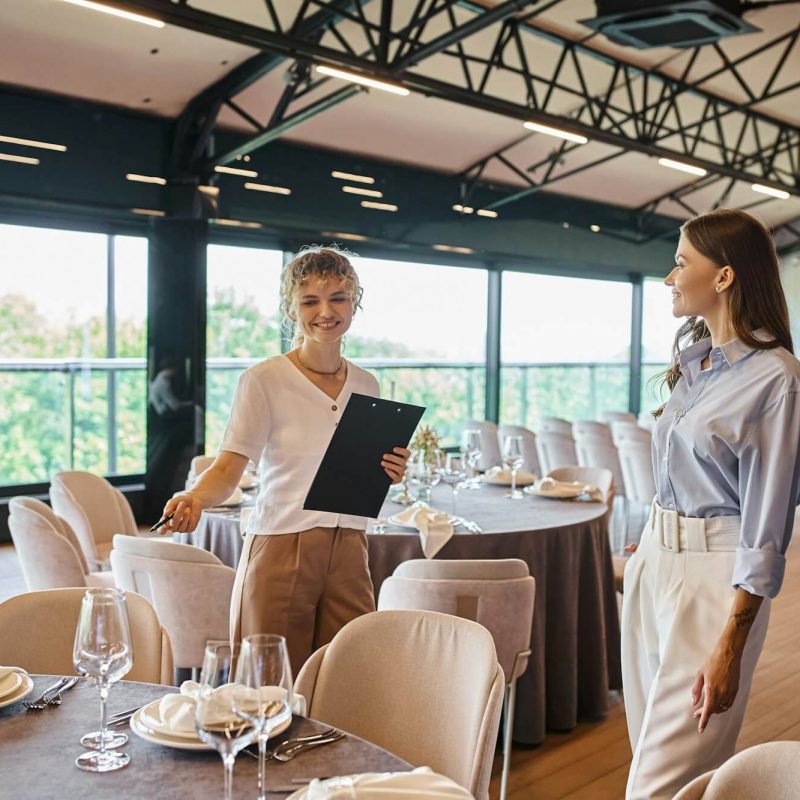 event-organizer-with-clipboard-pointing-at-table-with-festive-setting-near-woman-in-banquet-hall.jpg event-organizer-with-clipboard-pointing-at-table-with-festive-setting-near-woman-in-banquet-hall.jpg